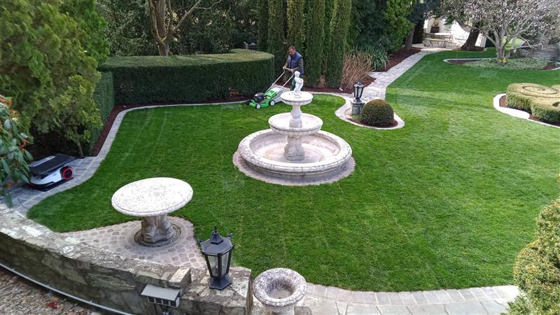 Rasenpflege im Parkgarten mit Brunnen